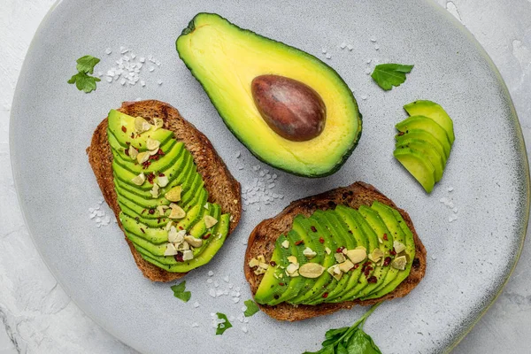 Avokado, çavdar ekmeği, dilimlenmiş avokado. Vejetaryen vejetaryen menüsü, tarif. Lezzetli kahvaltı ya da atıştırmalık, temiz yemek, diyet, vejetaryen yemek konsepti. en üstteki görünüm.