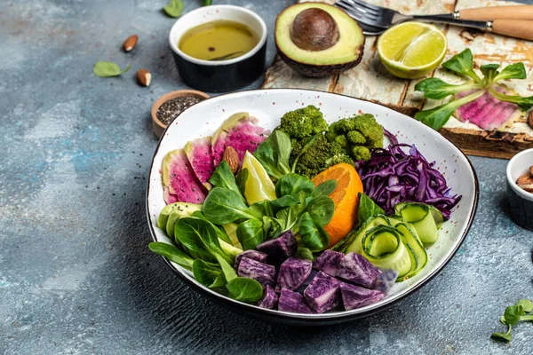 Tatlı patatesli vejetaryen salatası, brokoli, avokado, mor lahana, salatalık, karpuz turpu ve badem. Temiz yemek, diyet yemek konsepti. en üstteki görünüm