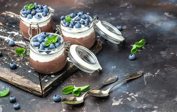 Delicious chocolate mousse or pudding with whipped cream. Chocolate panna cotta with blueberries. Chocolate pudding and greek yogurt parfait.