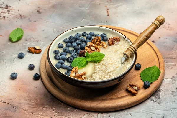 Kahvaltı için yulaf lapası, olgun yaban mersini, fındık ve bal dolu kaseleri kapat..