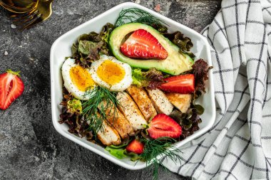 Sağlıklı besleyici paleo keto kahvaltı diyeti iki yumurta, avokado, ızgara tavuk fileto, fındık, çilek ve taze salata. Keto kahvaltısı ya da öğle yemeği. metin için yer, üst görünüm.