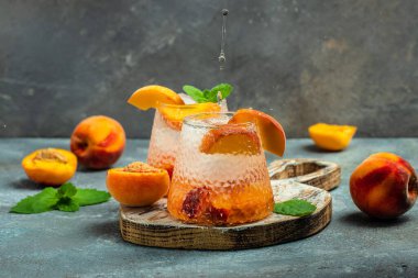 peach cocktail with ice cubes, and mint in glass. Freeze motion splash drops.
