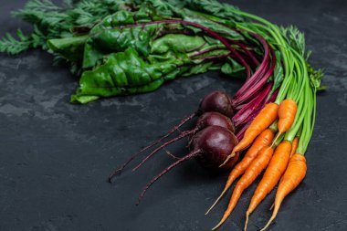 Bir sürü taze organik pancar kökü ve arka planda yeşil yapraklı havuç. Çiğ organik sebzeler, pankart, menü, metin için tarif yeri, üst görünüm,