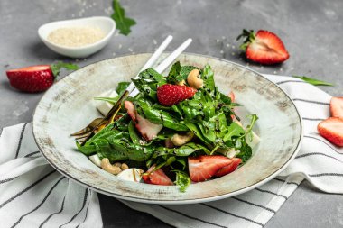 Ispanaklı çilek salatası, fındık, peynir, gri taşlı arka planda taze vejetaryen salatası, afiş, menü, yazı için tarif yeri, üst görünüm,