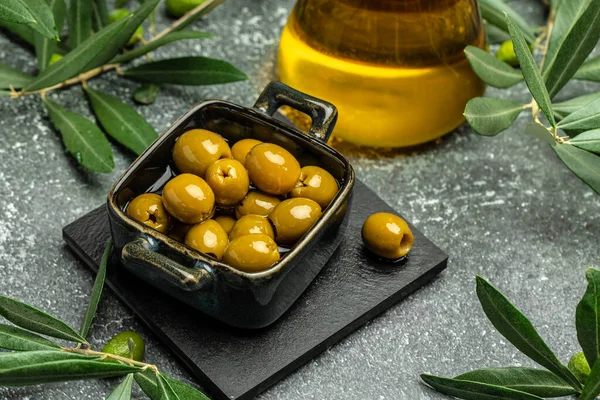 Branch with olives and a bottle of olive oil on dark background. top view. place for text,