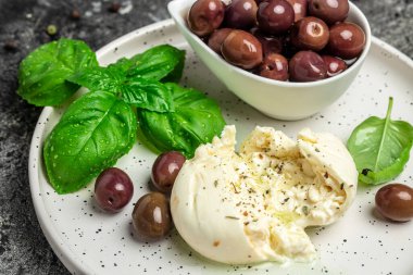 Beyaz tabakta fesleğenli ve zeytinyağlı kremalı İtalyan Burrata peyniri. İtalyan Akdeniz mutfağı. Yemek tarifi geçmişi. Kapat..