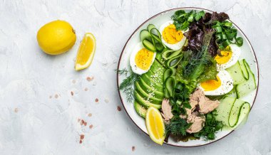 Ton balıklı vejetaryen Buda kâsesi avokado, yumurta, salatalık ve hafif arkaplanda taze salata. en üstteki görünüm.