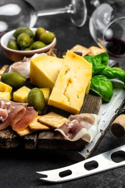 Antipasto tahtasını dilimlenmiş et, jambon, salam, peynir, zeytin ve şarapla kapatın. dikey görüntü. en üstteki görünüm.