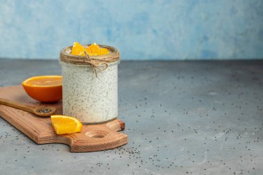 Narenciye ile süslenmiş camda laktozsuz yoğurt ile Chia Seed. Gri arka planda chia tohumlu yoğurt. sağlıklı süper yiyecekler. Sağlıklı yiyecekler. metin için yer.