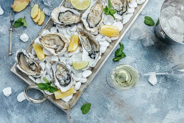 Opened oysters, ice on metal tray with lemon and ice. Restaurant menu, dieting, cookbook recipe,