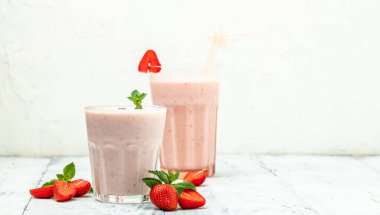 Meyveli smoothie. Çilekli smoothie ya da meyveli milkshake ve beyaz arka planda cam kavanozda yoğurt. Sağlıklı vejetaryen içeceği. Uzun afiş biçimi. en üstteki görünüm.