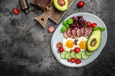 Sağlıklı besleyici paleo keto kahvaltı diyeti avokado, kızarmış yumurta, pastırma, fasulye ve kahve. Ketogenik diyet konsepti. Restoran menüsü, diyet, yemek kitabı tarifi üst görünümü.