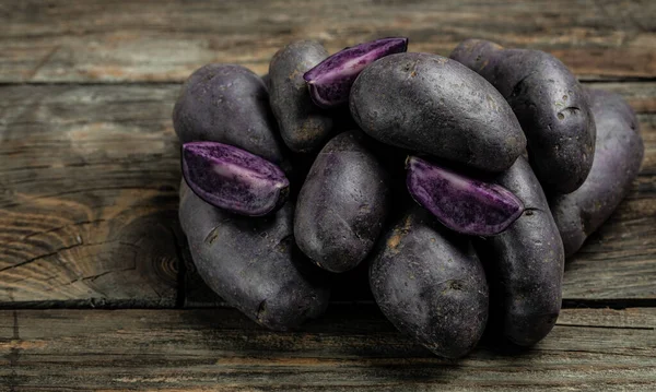 Purple sweet potatoes on wooden background, Batata potato. vegan food ingredient. banner, menu, recipe place for text, top view,