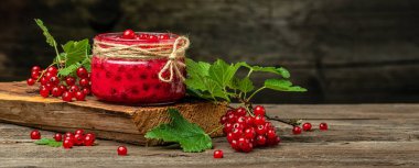 Kavanozda frenk üzümü reçeli. Ahşap arka planda taze meyve konservesi. Uzun pankart biçimi.