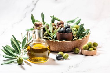 Ahşap kaselerde zeytin, arka planda cam şişelerde yağ. Sağlıklı ve detoks gıda konsepti.