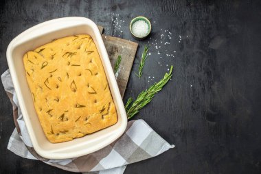 İtalyan yapımı ev yapımı Focaccia ekmeği biberiye ve zeytinyağlı. Esmer arka planda geleneksel İtalyan Focaccia 'sı. afiş, menü, metin için tarif yeri, üst görünüm.