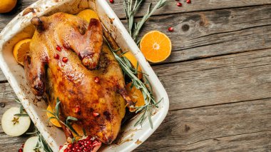 Köy ahşap masada, biberiyeli ve portakallı tam pişmiş ördek. Geleneksel kavrulmuş Noel Pekin ördeği.
