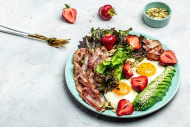 Fried egg bacon with avocado, strawberries and fresh salad, Ketogenic, keto or paleo diet, Delicious balanced food concept. place for text, top view.