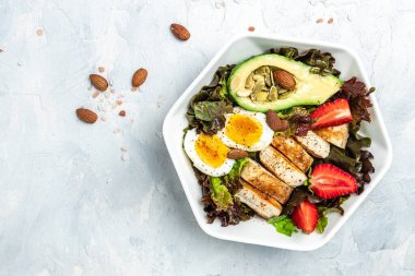 Ketojenik düşük karbonhidrat diyeti. Keto yiyecekli tabak: iki yumurta, avokado, ızgara tavuk fileto, fındık, çilek ve taze salata. Sağlıklı yağlar, kilo vermek için temiz yiyecekler. görünüm.