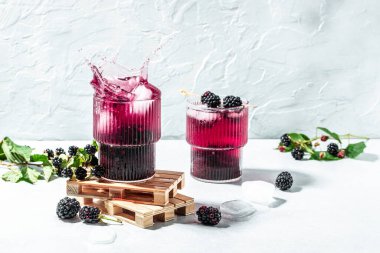 Blackberry mojito or lemonade with blackberry and ice Freeze motion splash drops on a light background. place for text.