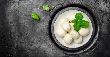 Koyu arkaplanda taze fesleğen yapraklı geleneksel mozzarella peyniri. Uzun afiş biçimi. en üstteki görünüm.