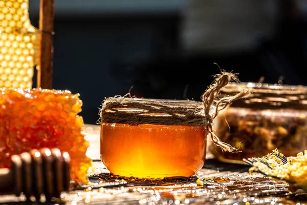 天然のハニカムと木製のテーブルの上のガラス瓶 蜂蜜の背景 ミツバチの製品は有機天然成分の概念によるもので — ストック写真