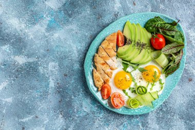 Kahvaltı Avokado, yumurta, kiraz domates, ızgara tavuk fileto, salatalık. Ketogenik diyet kahvaltısı. metin için yer, üst görünüm.