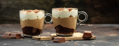 Tatlı üç çikolatalı mus, vanilyalı, çikolatalı, koyu arkaplanda kremalı brulee tatlısı. Uzun pankart biçimi.