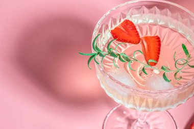 Pembe arka planda buzlu kokteyl içmek. Tazeleyici meyve kokteyli ya da şaraplı punç şampanya, çilek, buz ve biberiye.