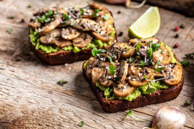 Avokado tostu, mantar ve mikroyeşil tam tahıllı sandviç. Susam ile süslenmiş. Vejetaryen yemeği. Vejetaryen menüsü. Yemek tarifi geçmişi. Kapat..