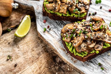 Avokado tostu, mantar ve mikroyeşil tam tahıllı sandviç. Susam ile süslenmiş. Vejetaryen yemeği. Vejetaryen menüsü. Yemek tarifi geçmişi. Kapat..