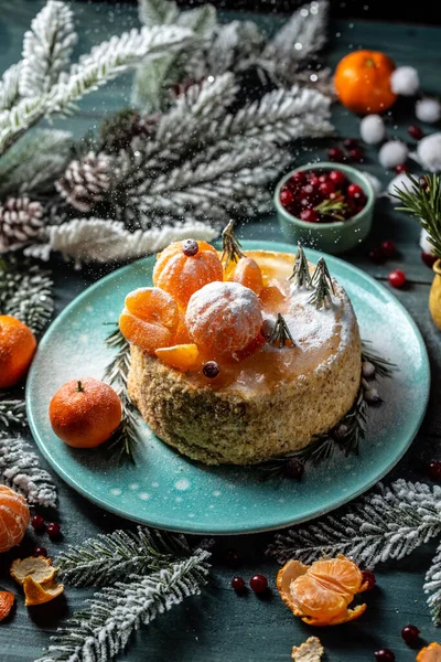 homemade christmas tangerines cake with white cream, fir tree branches on it stands. rosemary in the form of Christmas trees. atmospheric photo. vertical image.