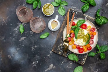 Traditional Italian dish burrata cheese with glass of rose wine. Burrata served with tomatoes and green pesto. place for text, top view.