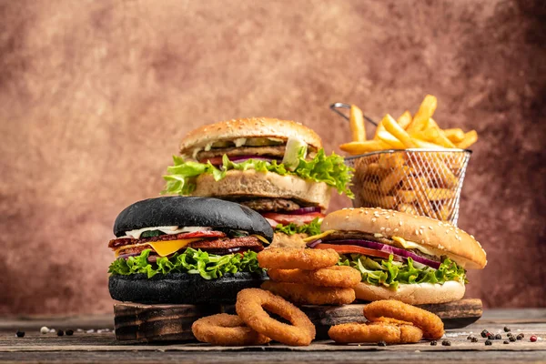 assortment of homemade burger with grilled meat, vegetables, sauce on rustic wooden background. fast food and junk food concept,