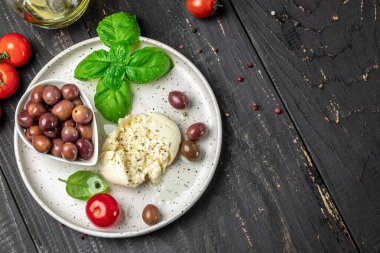 Beyaz tabakta fesleğenli ve zeytinyağlı kremalı İtalyan Burrata peyniri. İtalyan Akdeniz mutfağı. metin için yer, üst görünüm.