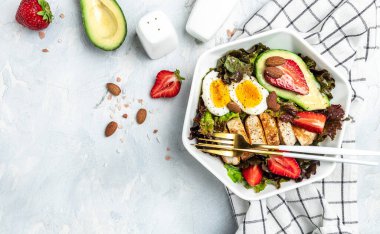 Keto kahvaltısı iki yumurta, avokado, çilek, ızgara tavuk fileto, fındık ve taze salata, ketogenik diyet. Keto diyet yemekli tabak. Sağlıklı gıda konsepti, üst görünüm.