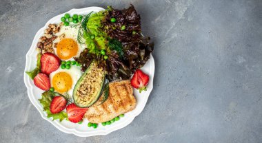 Sağlıklı besleyici paleo keto kahvaltı diyeti kızarmış yumurta, avokado, ızgara tavuk fileto, fındık, çilek ve taze salata. Keto kahvaltısı ya da öğle yemeği. Uzun afiş biçimi. en üstteki görünüm,
