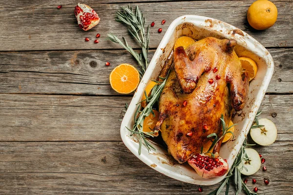 Roast Christmas duck with rosemary, thyme, berries and apples on rustic wooden table, banner, menu, recipe place for text, top view,