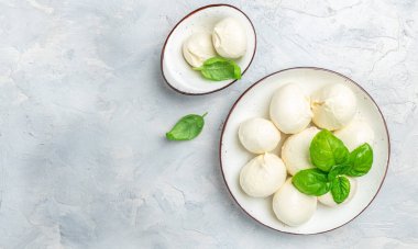 Peynir koleksiyonu, beyaz İtalyan peynirli mozzarella topları, arka planda taze fesleğen yapraklarıyla servis edilmiş, yazı için yer, üst manzara.,