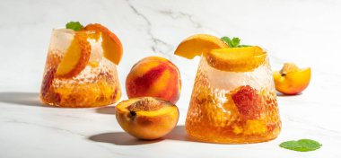 Refreshing Peach Bourbon Smash Cocktail with ice cubes, and mint in glass. Long banner format.