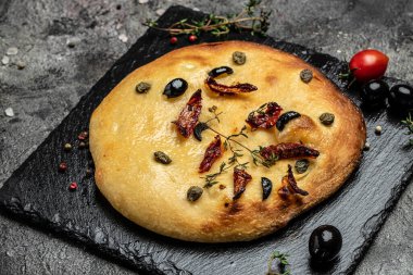 Zeytinyağlı Focaccia ekmeği, zeytin, güneşte kurutulmuş domates, kapari ve kekik.