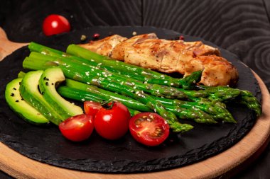 Ketogenik diyet kahvaltısı. Salata, taze domates, kuşkonmaz ve avokado ile ızgara tavuk filetosu. Sağlıklı yemekler, diyet menüsü. Kopyalama alanı olan uzun biçim.