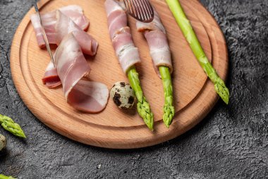 Kuşkonmaz ve pastırma koyu bir arka planda pişmeye hazır. Keto Paleo diyeti. afiş, menü, metin için tarif yeri, üst görünüm.