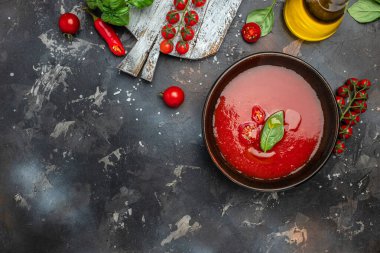 Arka planda fesleğenli püre domates çorbası. Temiz yemek, diyet, vejetaryen yemek konsepti. en üstteki görünüm.