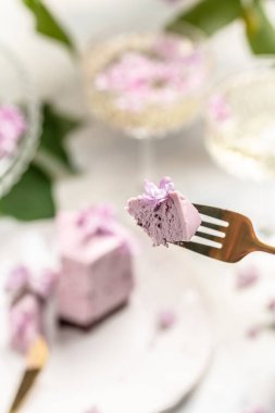 Bir parça kremalı pasta, taze böğürtlenli lezzetli tatlı yaban mersinli tart ve bir buket mor çiçek açan leylak.,