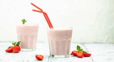 Two glasses of Strawberry smoothie or milkshake with berries and yogurt on white background. Vegetarian healthy drink. place for text,