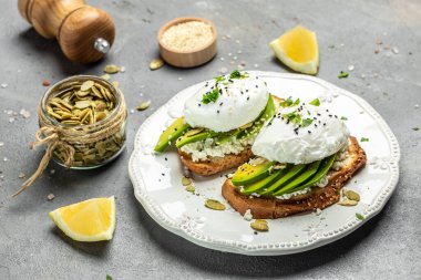 Avokadolu kızarmış ekmek, haşlanmış yumurta, yumuşak peynir ve kabak çekirdeği. Temiz yeme konsepti. Vejetaryen ya da glütensiz diyet. en üstteki görünüm,
