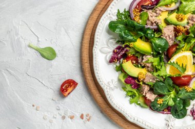 Ton balıklı salata, avokado, marul, arka planda vişneli domates. Restoran menüsü, diyet, yemek kitabı tarifi üst görünümü.