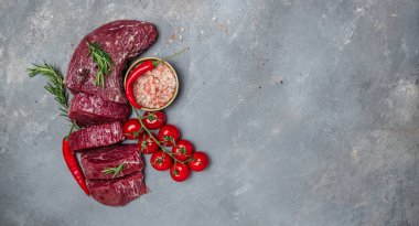 Karanlık bir arka planda sığır eti, biftek ve baharatla pişirilmeye hazır bir parça fileto.,