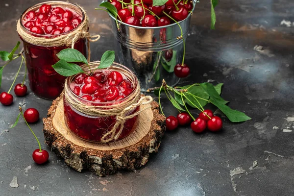 Fresh red cherries fruit on wooden background. Jar of cherry jam and sour cherries. Berries cherry with syrup. Canned fruit. place for text, top view.